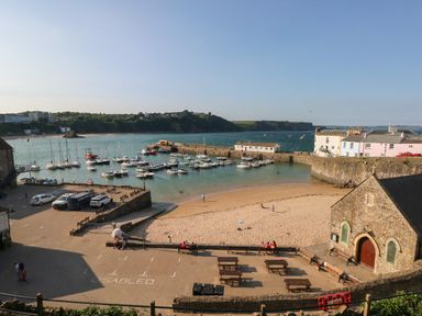 A small harbor with boats docked near a sandy beach and stone buildings at Stones Throw in Tenby