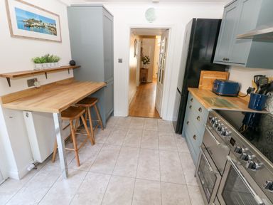 A kitchen with wooden countertops stools a black refrigerator a stove and kitchen utensils at Stones Throw in Tenby