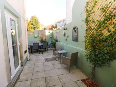 A patio area with outdoor chairs tables wall decorations and plants at Stones Throw in Tenby