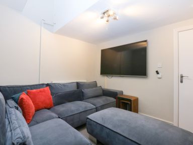 A living room with a sofa and television at Oak Cottage in Dinas Dinlle near Caernarfon