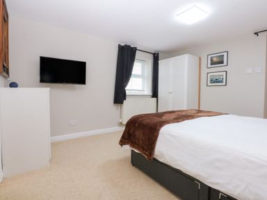 A bedroom with a bed and wardrobe at Oak Cottage Dinas Dinlle near Caernarfon