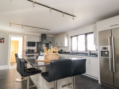 A kitchen with black chairs a basket on the island and stainless steel refrigerator at Mill End in Eamont Bridge near Penrith