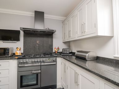 A kitchen with a stove oven microwave toaster bread box and white cabinets at Mill End in Eamont Bridge near Penrith