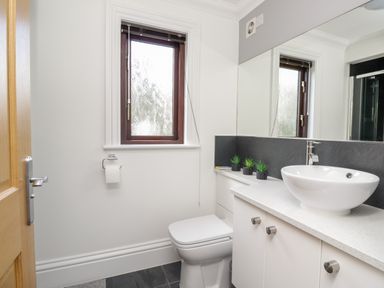 A bathroom with a toilet a sink countertop with cabinets and a window at Mill End in Eamont Bridge near Penrith