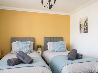 A bedroom with two single beds with gray headboards and blue pillows at Mill End in Eamont Bridge near Penrith