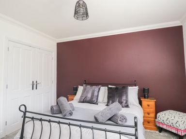 A bedroom with a bed with rolled towels pillows and two wooden bedside tables with lamps at Mill End in Eamont Bridge near Penrith