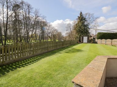 A long grassy garden with a wooden fence and a shed at the end at Mill End in Eamont Bridge near Penrith