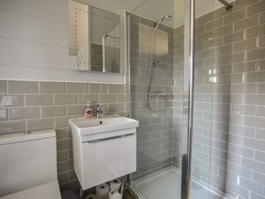 A bathroom with a shower enclosure sink with tap and soap dispenser a toilet and toilet rolls at Oakwood 2 @ Pinewood Retreat in Pinewood