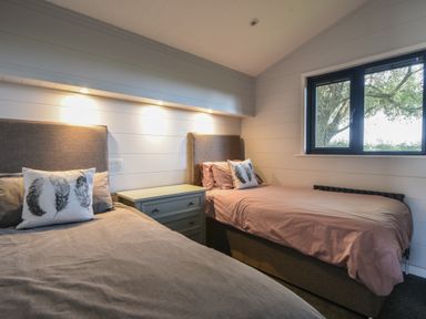 A bedroom with two single beds a bedside table and a window showing a tree outside at Oakwood 2 Pinewood Retreat in Pinewood