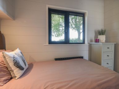 A bedroom with a bed a bedside cabinet a window and a plant at Oakwood 2 @ Pinewood Retreat in Pinewood