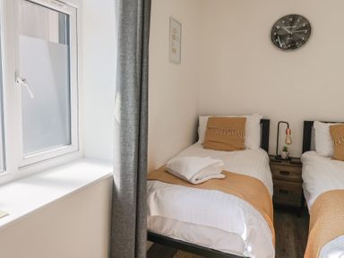 A bedroom with two single beds and a window at Lyme Zest in Lyme Regis
