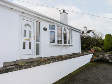 The exterior of a white house with a white door and windows neudd wen red wharf bay near benllech