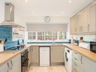 A kitchen with appliances and blue tiled backsplash at Neaudd Wen in Red Wharf Bay near Benllech