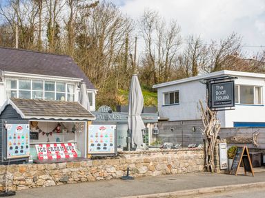 An ice cream hut and a cafe restaurant named The Boat House with outdoor seating and signage at Neaudd Wen Red Wharf Bay near Benllech