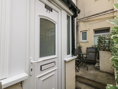 A door leading to a patio area with a table and chairs at Saddlers Cottage in Weymouth