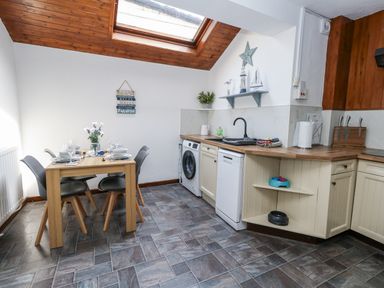 A kitchen with a dining table and appliances at Saddlers Cottage in Weymouth