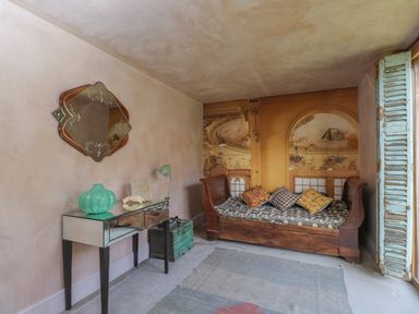 A room with a wooden daybed with cushions and a mirrored console table with a green vase at Brandeers Long Barn Brandier near Minety