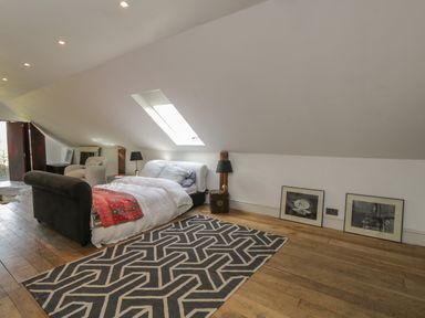 A bedroom with a bed next to a skylight window and two framed pictures on the floor at Brandeers Long Barn in Brandier near Minety
