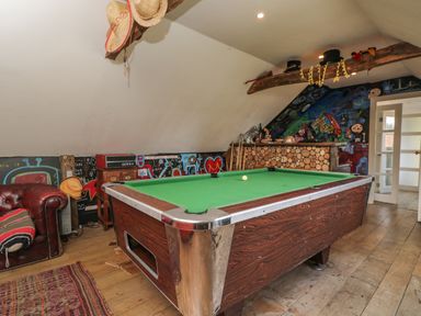 A game room with a pool table a leather sofa and colorful graffiti on the walls at Brandeers Long Barn Brandier near Minety