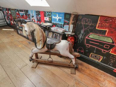 A room with a wooden rocking horse and a bookshelf with board games and DVDs at Brandeers Long Barn Brandier near Minety
