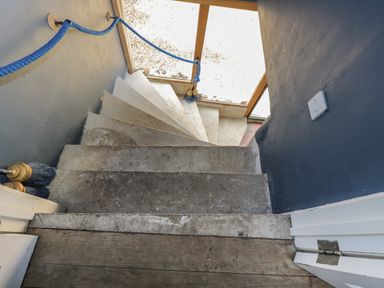 A concrete spiral staircase with a blue rope handrail inside a building at Brandeers Long Barn in Brandier near Minety