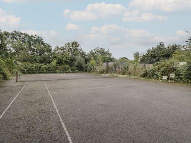 An outdoor tennis court surrounded by trees and bushes at Brandeers Long Barn in Brandier near Minety