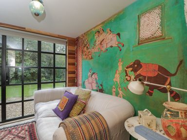 A room with a white sofa and colorful pillows next to a painted wall and a window at The Big Box Brandeers Brandier near Minety