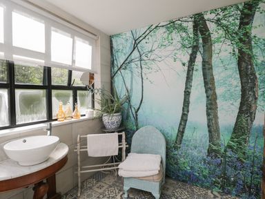A bathroom with a sink countertop mirror potted plant towel rack and a chair with towels at The Big Box Brandeers Brandier near Minety