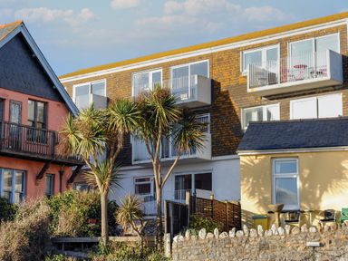 A group of buildings with balconies and palm trees in front at 3 Bay View Court in Lyme Regis