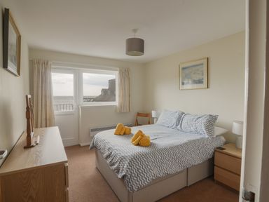 A bedroom with a double bed and yellow towels on it a dresser and two lamps by the bed at 3 Bay View Court Lyme Regis