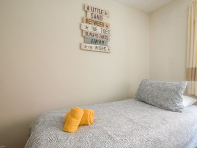 A bedroom with a single bed a pillow two orange towels and a wall decoration at 3 Bay View Court in Lyme Regis