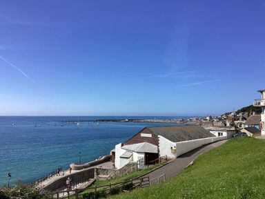 A coastal view with a marine theatre building pathway and sea with sailboats at 3 Bay View Court in Lyme Regis