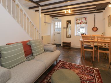 A living room with a sofa green cushions dining table and chairs near a window at Henfro in Beddgelert