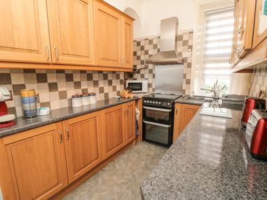 A kitchen with wooden cabinets a stove microwave sink and countertop appliances at The Seahome in Scarborough