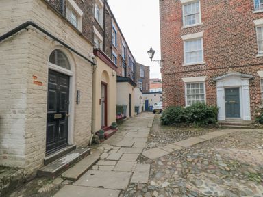 A narrow cobblestone street with brick buildings and arched doorways at The Seahome in Scarborough