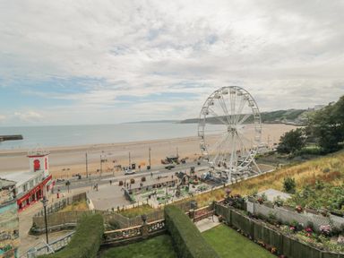 A beach with a Ferris wheel playground and a red and white building near the shore at The Seahome in Scarborough