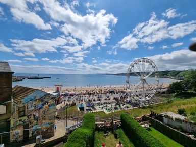 A beach view with a ferris wheel and people on the sand at The Seahome in Scarborough