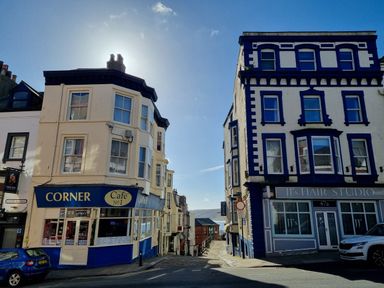 A street view with Corner Cafe and JJ's Hair Studio buildings showing a pathway to the water at The Seahome in Scarborough