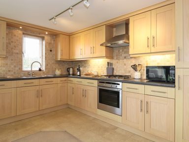 A kitchen with wooden cabinets a gas stove oven microwave and a sink at Chase View Bowland Bridge near Bowness-On-Windermere