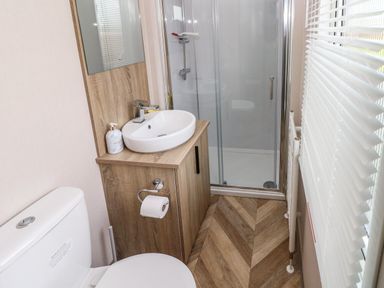A bathroom with a toilet sink cabinet shower and window blinds at The Waves in Little Haven near Broad Haven