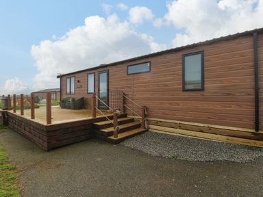 A wooden cabin with a deck and steps outside at The Waves Little Haven near Broad Haven