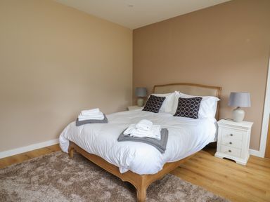 A bedroom with a bed pillows nightstands and lamps at Heritage in St Clears