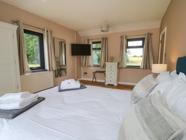 A bedroom with a bed a wardrobe a chest of drawers and windows at Heritage St Clears