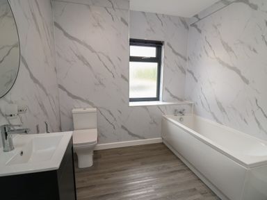 A bathroom with a bathtub a toilet a sink a mirror and a window at Heritage in St Clears