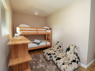 A bedroom with wooden bunk beds two bean bags a carpet and a wooden shelf with a lamp at Heritage in St Clears