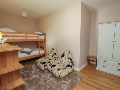 A bedroom with bunk beds two patterned bean bags a wooden wardrobe and a wooden shelving unit at Heritage in St Clears