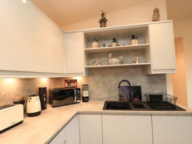 A kitchen countertop with a toaster kettle microwave and dish rack at Pine Marten in Dornoch