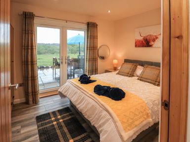A bedroom with a bed pillows and towels near a glass door leading to a patio at Pine Marten in Dornoch
