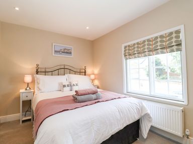 A bedroom with a double bed bedside tables with lamps window with patterned blind at Cavan Cottage in Yoxford