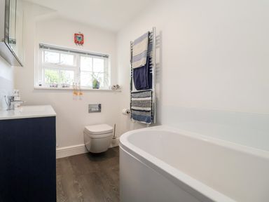 A bathroom with a bathtub toilet sink and a window with plants on the sill at Cavan Cottage in Yoxford